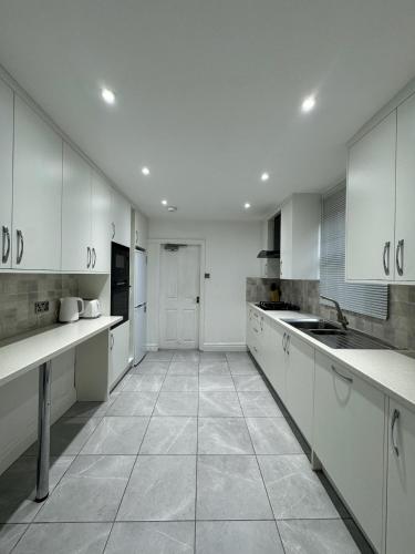 a large kitchen with white cabinets and a tile floor at St Helens House Incredible Location with Parking & Garden in Oxford