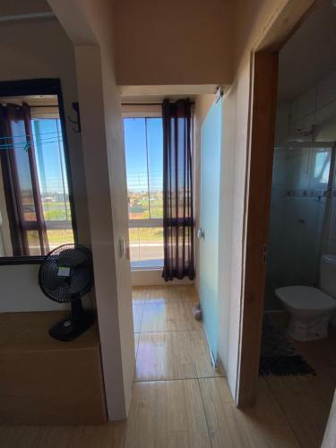 a hallway with a bathroom with a toilet and a window at Apartamento em Torres RS in Torres