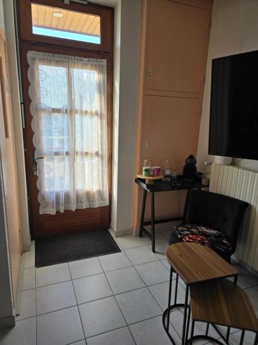 a living room with a door and a chair and a table at Chambre indépendante in Les Avenières