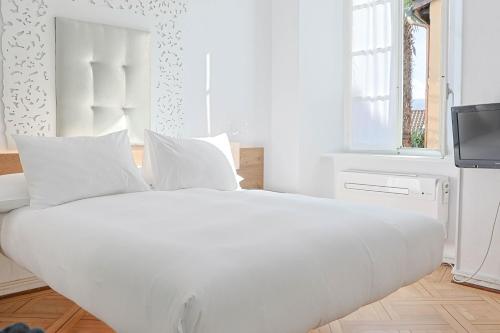 a white bed with white pillows in a bedroom at Caffè dell'Arte Boutique Rooms Locarno in Locarno