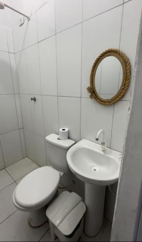a white bathroom with a toilet and a sink at Pousada Moranga in Carolina