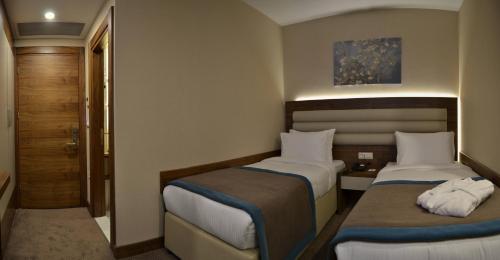 a small room with two beds and a door at Görükle Güler Park Hotel in Gorukle