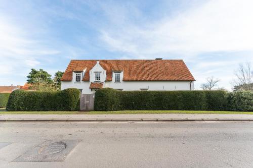 a white house with a red roof on a street at Endless summer Knokke - Pool Villa in Knokke-Heist