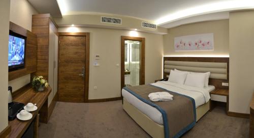 a hotel room with a bed and a flat screen tv at Görükle Güler Park Hotel in Gorukle