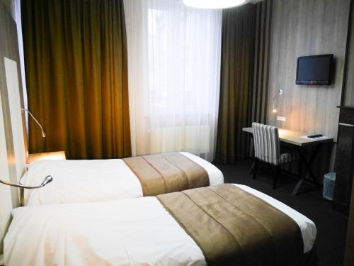 ルーヴェンにあるホテル ミル コロンのベッド2台とデスクが備わるホテルルームです。