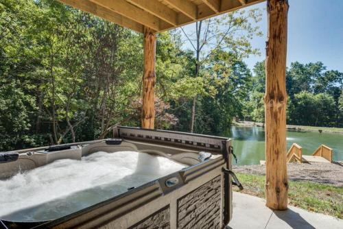una vasca idromassaggio sotto un pergolato in legno accanto a un fiume di Stone Lake Lodge - Lakeside Cabin - Stocked Pond a Coshocton