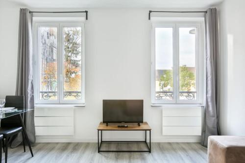 - un salon avec une télévision et 2 fenêtres dans l'établissement Suite Lumineux et Moderne, Parking Gratuit, MULHOUSE CENTRE, à Mulhouse