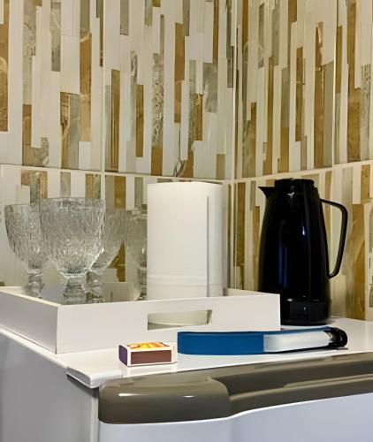 a white shelf with glasses and a vase on it at Acesso à Praia Ar Condicionado Conforto Garantido! in Saquarema