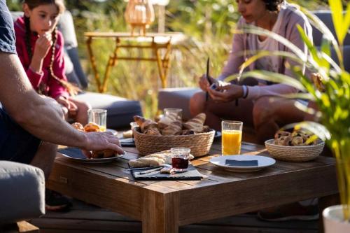 Un groupe de personnes assises autour d'une table avec de la nourriture dans l'établissement Camping 4 étoiles - Parc aquatique - ef0bbb, aux Mathes