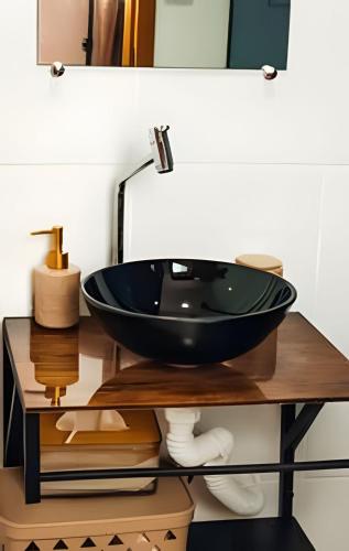 a bathroom with a black bowl sink on a table at Acesso à Praia Ar Condicionado Conforto Garantido! in Saquarema