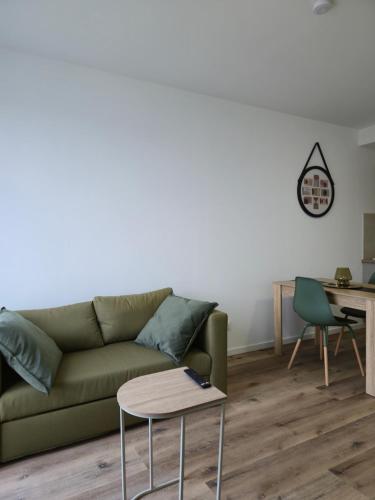 un salon avec un canapé vert et une table dans l'établissement 303 - Strasbourg appartement Green refait à neuf, à Strasbourg