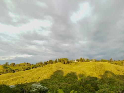 a grassy hill with a house on top of it at Green Highland Casa Campestre in Pereira