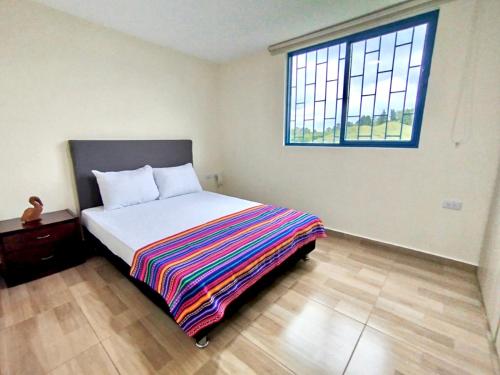 a bedroom with a bed with a colorful blanket on it at Green Highland Casa Campestre in Pereira