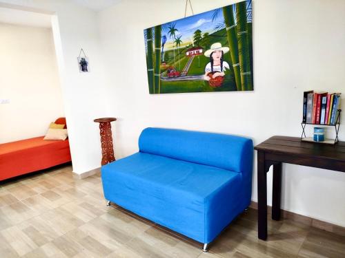 a blue chair in a room with a table and a painting at Green Highland Casa Campestre in Pereira