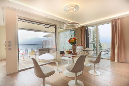 a dining room with a table and chairs and a balcony at Montreux Lake View Apartments and Spa - Swiss Hotel Apartments in Montreux
