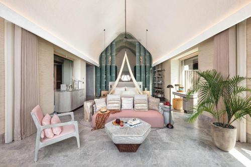a bedroom with a bed and a couch and a chair at JOALI BEING in Raa Atoll