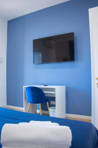 a bedroom with a blue wall with a bed and a tv at WANDERLUST SPACCANAPOLI Points Of View in Naples