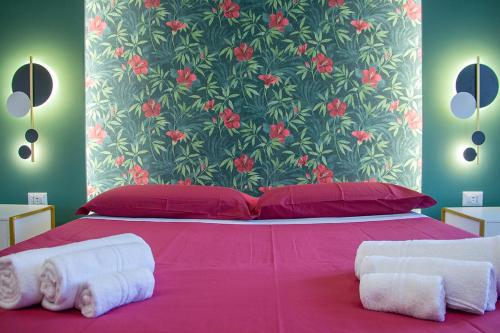 a bedroom with a pink bed with red pillows and a floral wall at WANDERLUST SPACCANAPOLI Points Of View in Naples