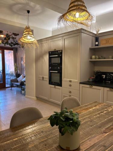 une cuisine avec une table en bois, des chaises et deux lumières dans l'établissement Maison Louisa, à Saint-Paul-de-Vence