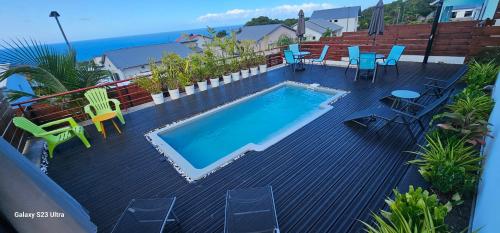 a swimming pool on a deck with chairs and a table at Villa Rosie in Sainte-Rose