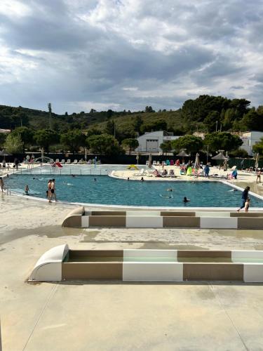 une grande piscine avec des gens dans l'eau dans l'établissement Location Mobilhome, à Narbonne-Plage