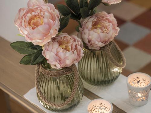 three vases with pink flowers on a table with candles at Apparthotel "Landhaus Veronika" in Mayrhofen