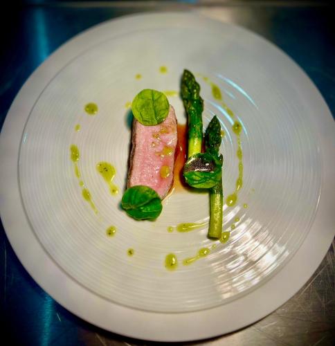 a white plate with a piece of meat and asparagus at Richard Lequet Domaine gastronomique du Val d Atur in Boulazac