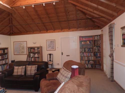 a living room with two couches and bookshelves at The Old Cottage in Arduaine