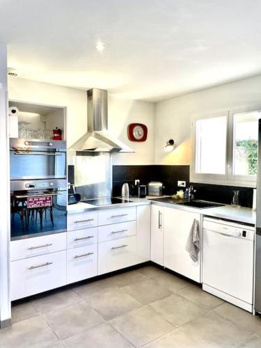 une grande cuisine avec des armoires blanches et une table dans l'établissement Villa Florebo 3 chambres Confort, Calme et Charme, à Gujan-Mestras