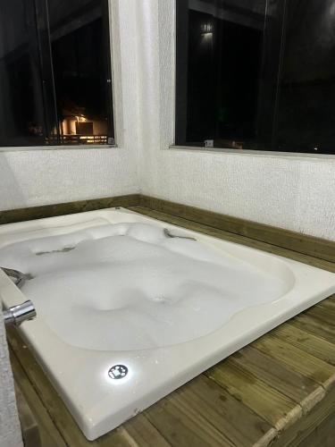a bath tub in a bathroom with two windows at Por do sol Boiçucanga in São Sebastião