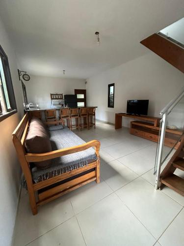 a living room with a bed and a television at Por do sol Boiçucanga in São Sebastião