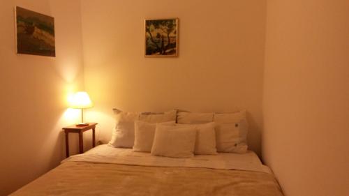 ein Schlafzimmer mit einem Bett mit weißen Kissen und einer Lampe in der Unterkunft Old Harbour City Center Apartment in Dubrovnik