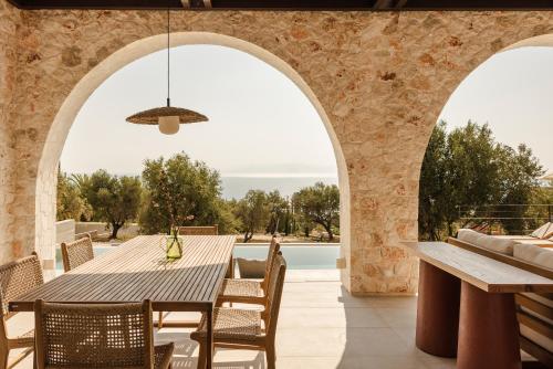 an outdoor dining area with a table and chairs and a stone wall at Kerami Kefalonia in Kefallonia