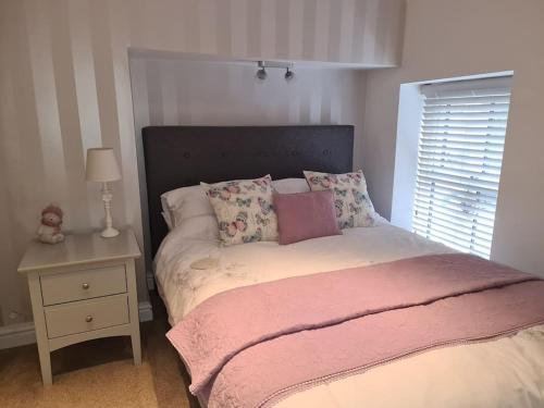 a bedroom with a bed with a pink blanket on it at Bear Cottage Cosy little place in the heart Ingleton in Ingleton