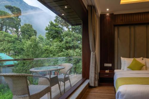 a room with a balcony with a table and chairs at Alt Life Luxe - Himalayan Crown - Dharamkot Mcleodganj in Dharamshala