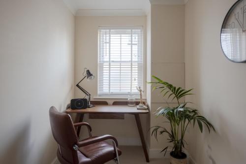 チェルムスフォードにあるModern 2 bed town house quiet street near stationの机と椅子と窓のあるオフィス
