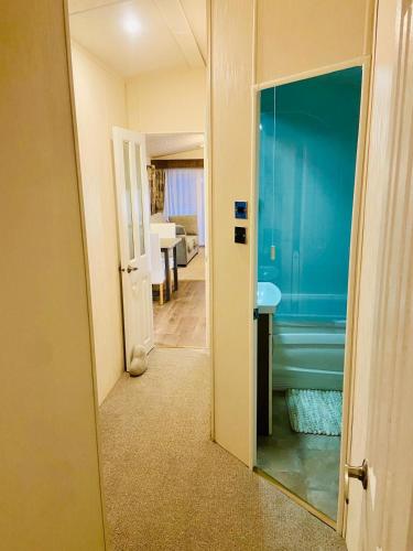 a hallway with a bathroom with a sink and a mirror at Lakeside mini lodge in Saint Osyth