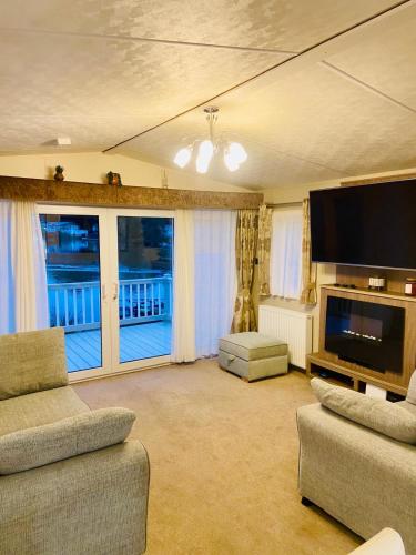 a living room with a flat screen tv and a couch at Lakeside mini lodge in Saint Osyth