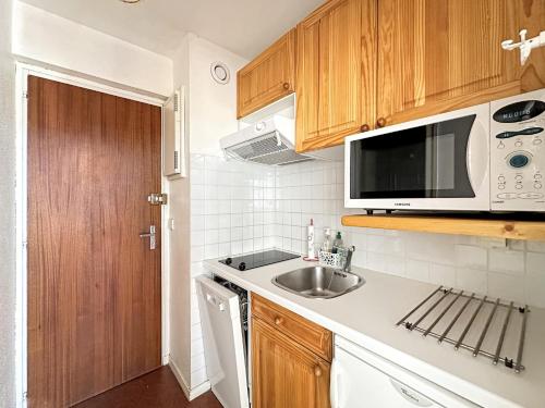 une petite cuisine avec un évier et un micro-ondes dans l'établissement CL339 - Appartement 6 personnes centre village, aux Carroz d'Arâches