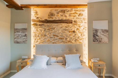 a bedroom with a white bed and a stone wall at Hotel Mas De Cebrian in Puertomingalvo