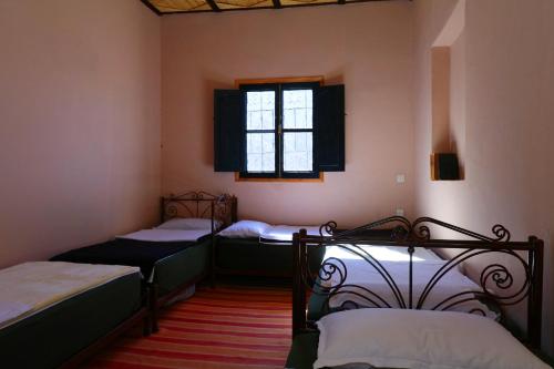 two beds in a room with a window at Gite Ogog Tacheddirt in Tacheddirt