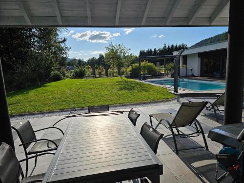 un patio avec une table et des chaises à côté d'une piscine dans l'établissement Le treizième ciel !, à Gérardmer