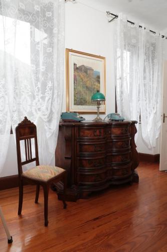 a chair and a dresser in a room with curtains at casa margherita in Pieve di Teco