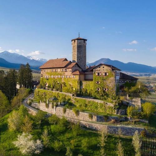 a large building on top of a hill with grass at Living with style between mountains & apple orchards in Tuenno