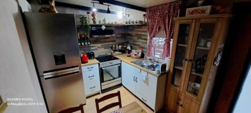 a kitchen with a stainless steel refrigerator and white cabinets at Zoe garden home in Spáta