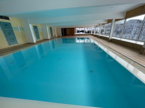 a large swimming pool with blue water in a building at White Rose apartment in Kulmhof in Tauplitz