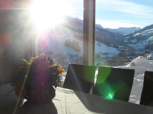 a person sitting at a table with a view of a mountain at Appartementhaus Casamarai in Saalbach Hinterglemm