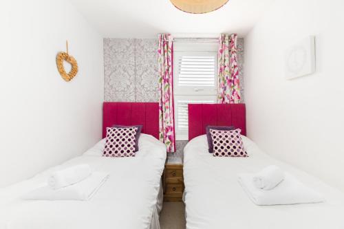 two beds in a small room with pink accents at Arden Holiday Lettings in Stratford-upon-Avon