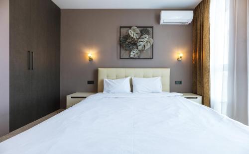 a bedroom with a large white bed with two tables at Nyvky Like Home - Файна Таун з басейном - Кв 398 in Kyiv
