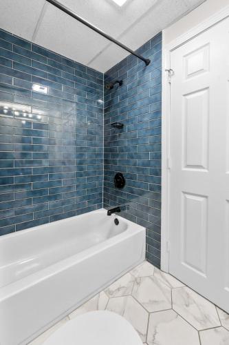 a bathroom with a white tub and blue tiles at Green Harbor Hotel in Marshfield